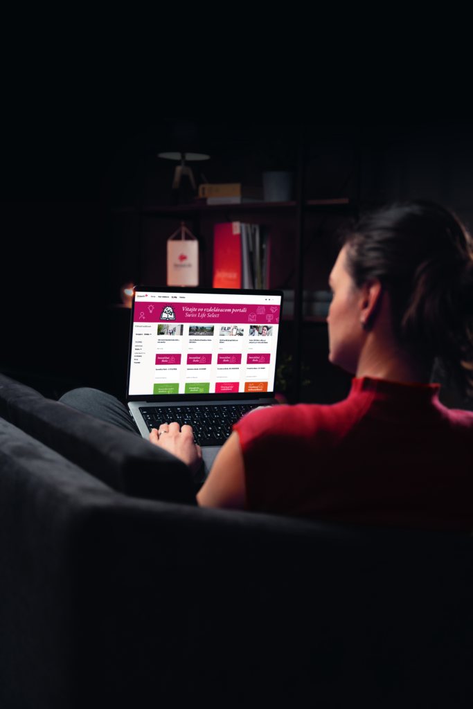 Woman viewing Swiss Life Select LMS dashboard on a laptop in a dimly lit room