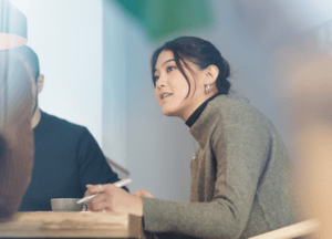 Woman taking notes while listening to colleagues in a meeting